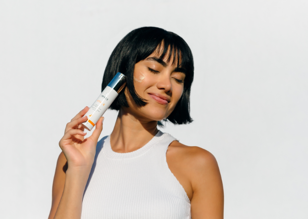 A happy woman holding a bottle of Image Skincare